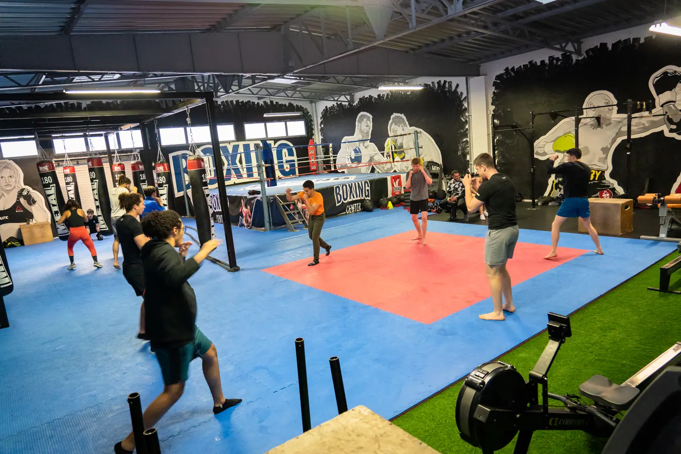 Un cours collectif sur tout le plateau : binômes en garde, sacs et ring au fond