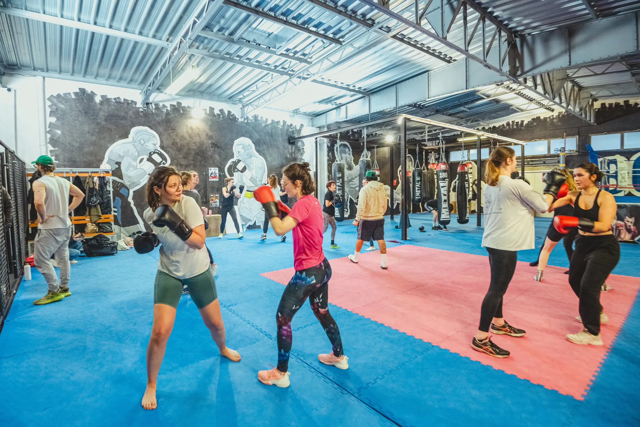 Un cours en plein travail sur le plateau : binômes en garde sur les tapis bleu et rouge