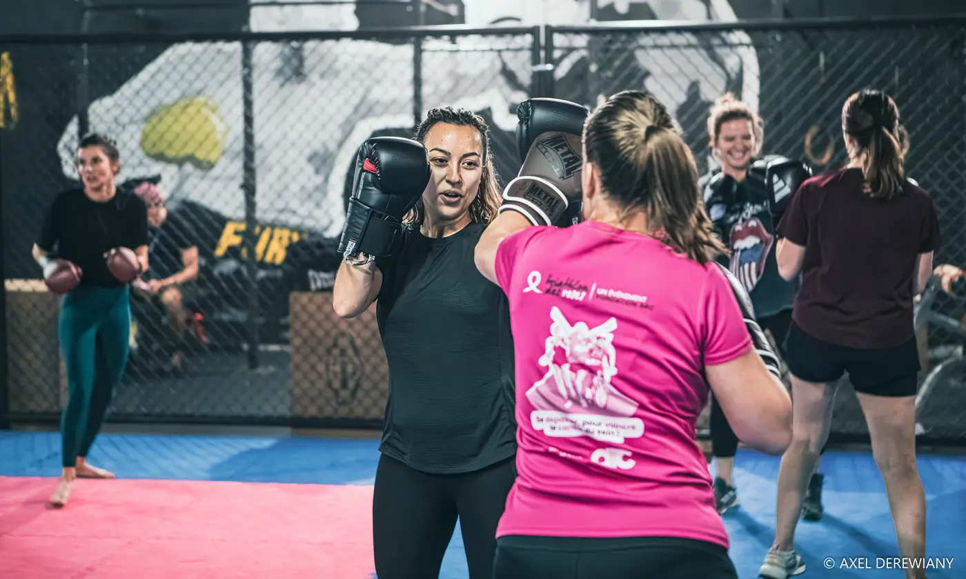 Un cours Lady Punch dans la cage : deux pratiquantes travaillent en binôme, gants aux mains