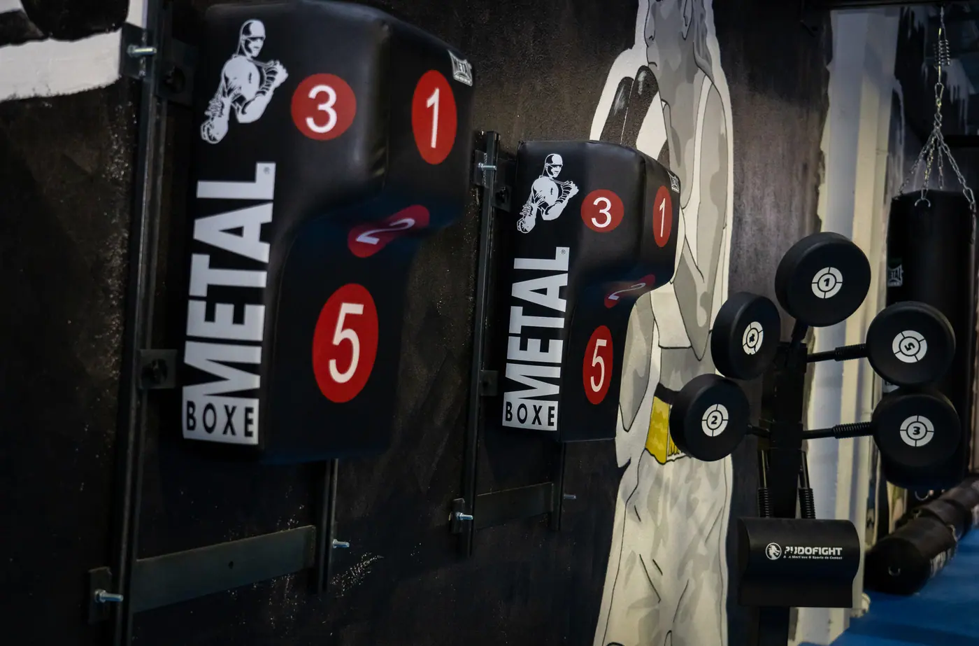 Une cible murale Metal Boxe numérotée 1, 3 et 5 et une tour de cibles rondes numérotées, fixées sur un mur peint